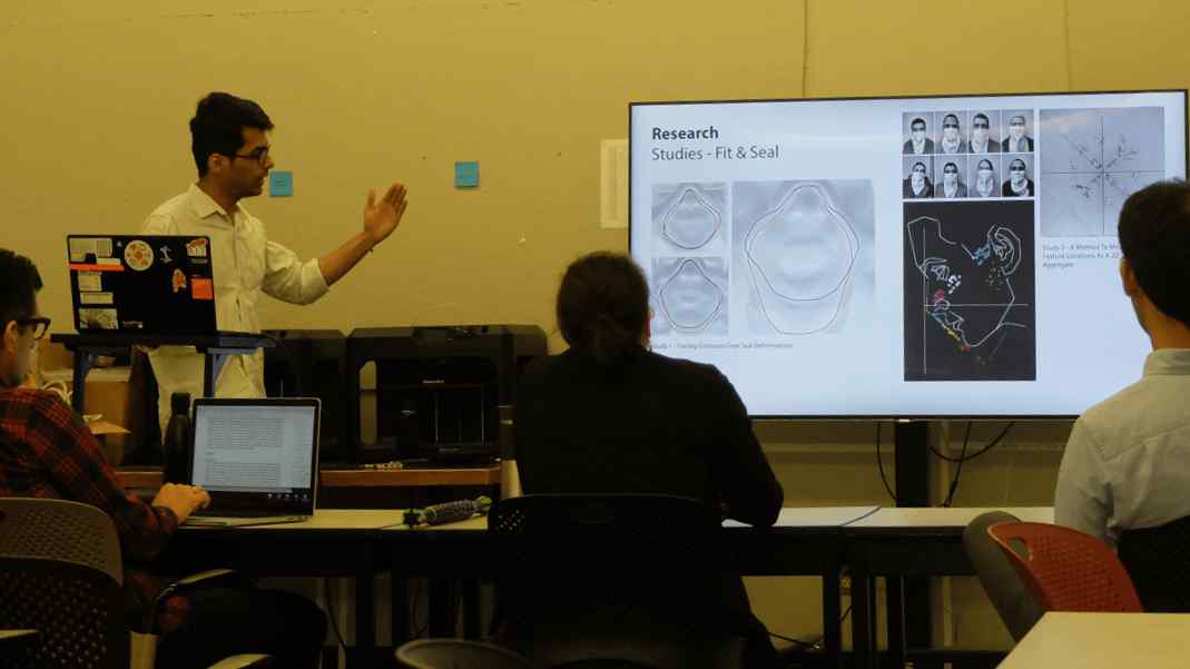 photo of a person presenting to a thesis panel of three people