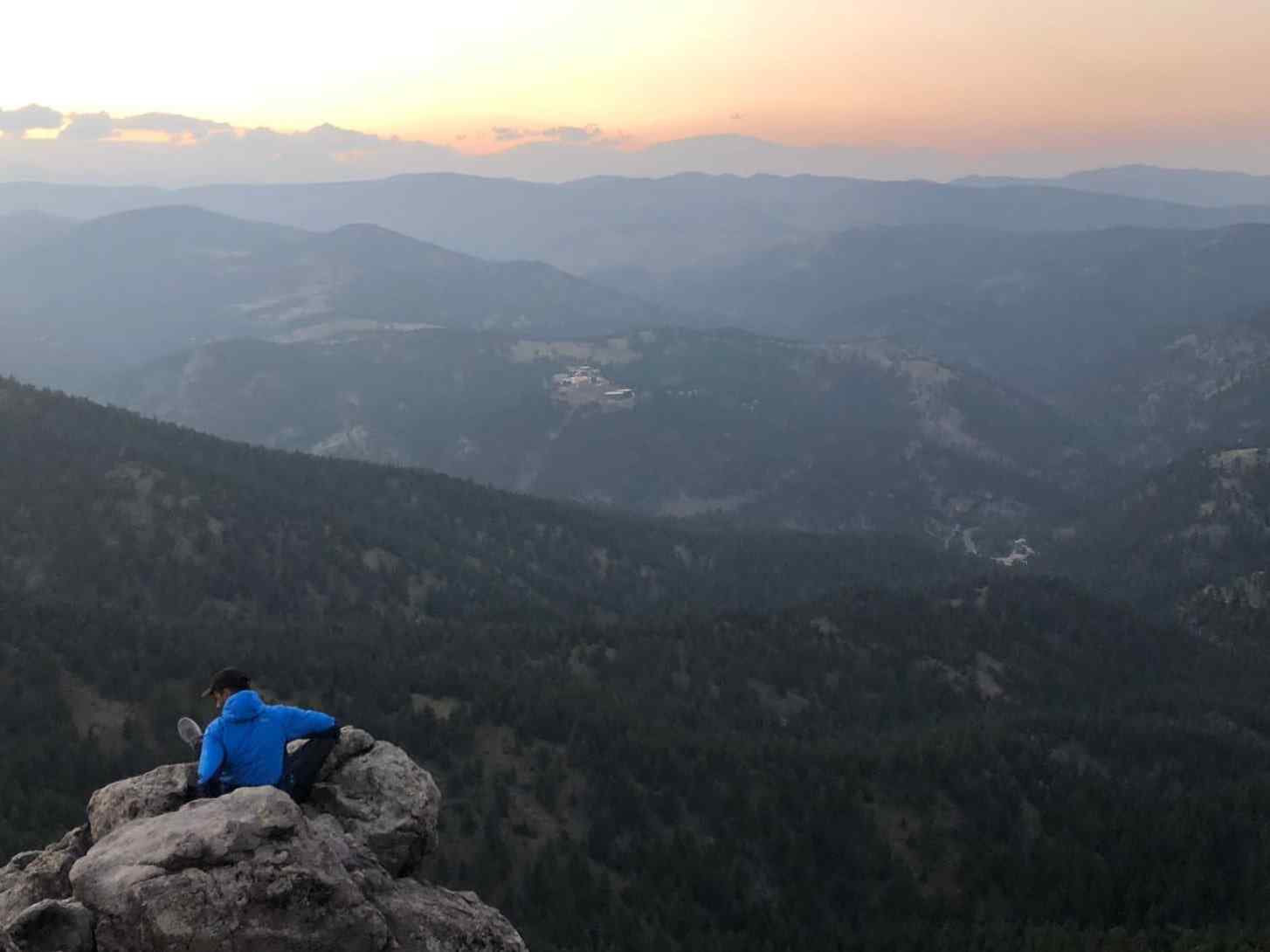 photo of person sitting on a rocky cliff of a mountain